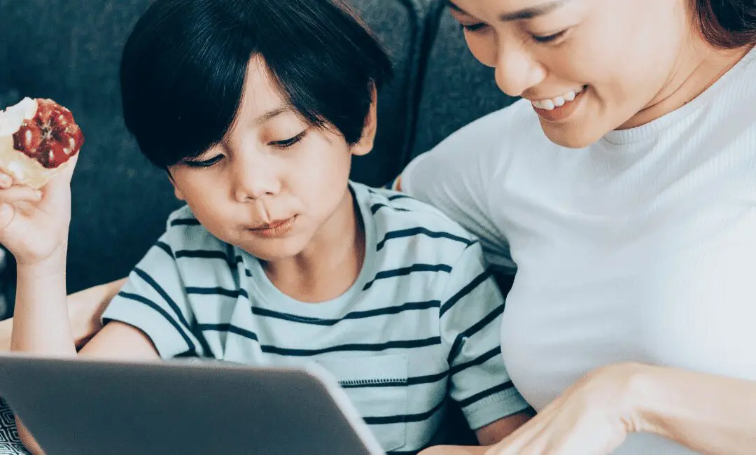 A mum and boy sitting on the sofa looking at a laptop