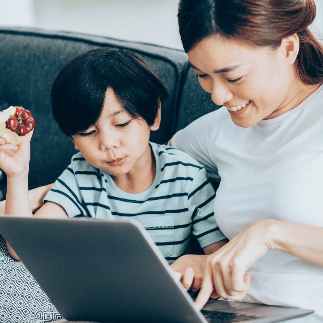 A mum and boy sitting on the sofa looking at a laptop