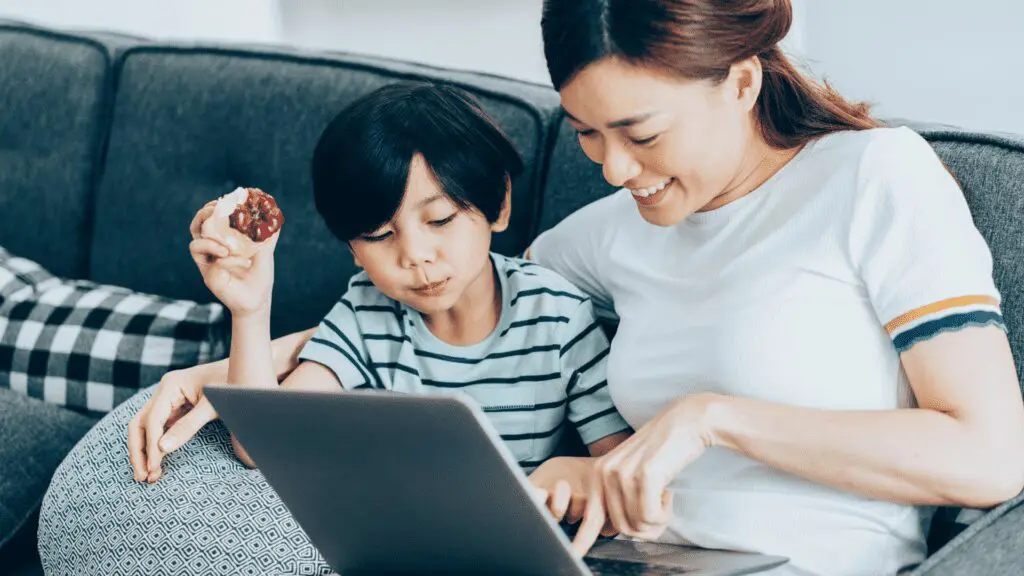 A mum and boy sitting on the sofa looking at a laptop